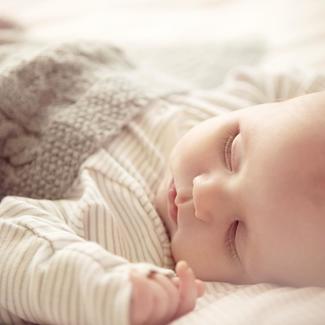 Baby wrapped in knit blanket, sleeping