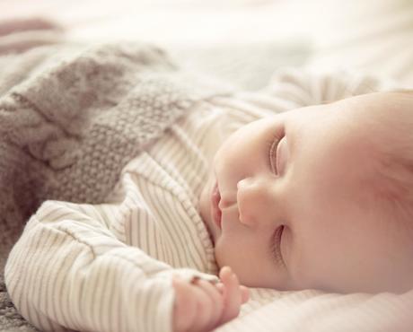 Baby wrapped in knit blanket, sleeping