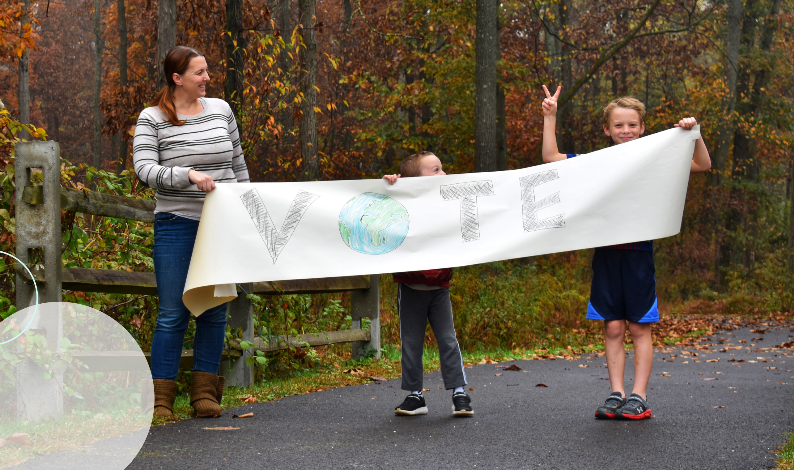 Adult and children with homemade VOTE banner standing outside