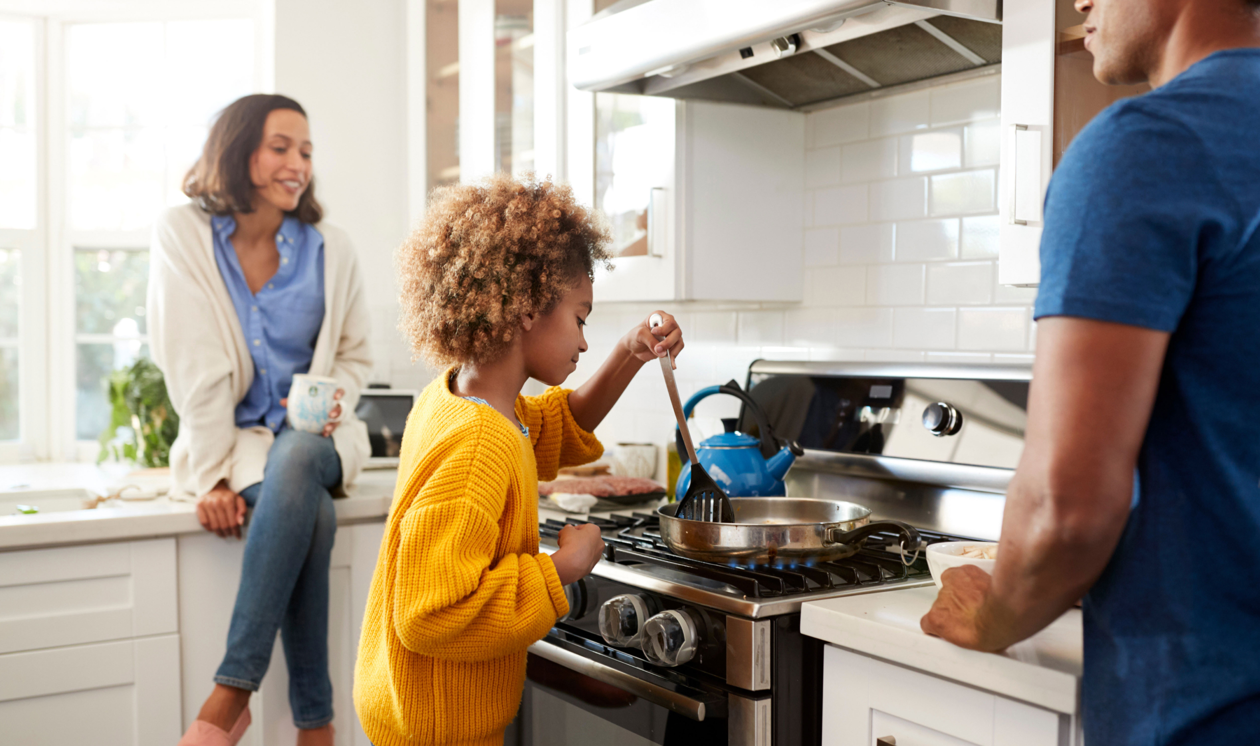 Family cooking together at gas stove