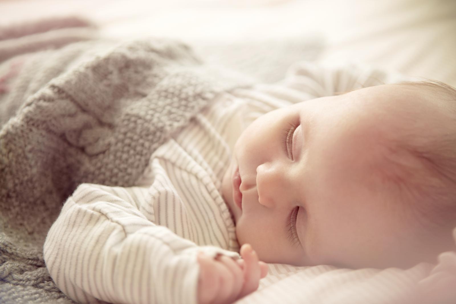 Baby wrapped in knit blanket, sleeping