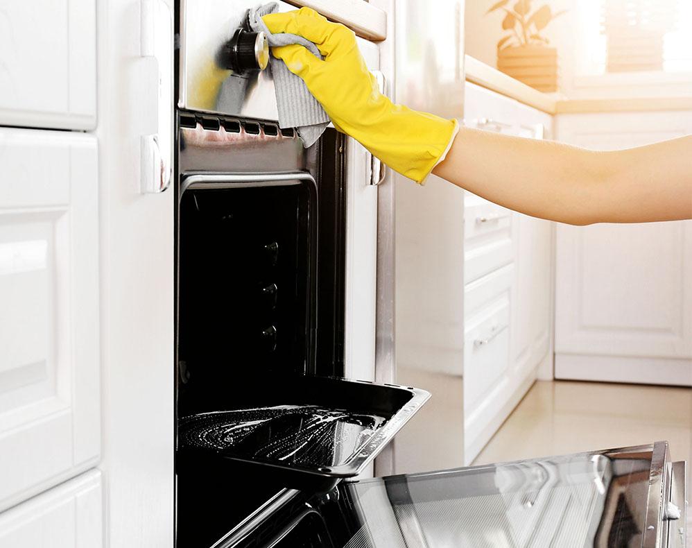 Person cleaning oven with gloves