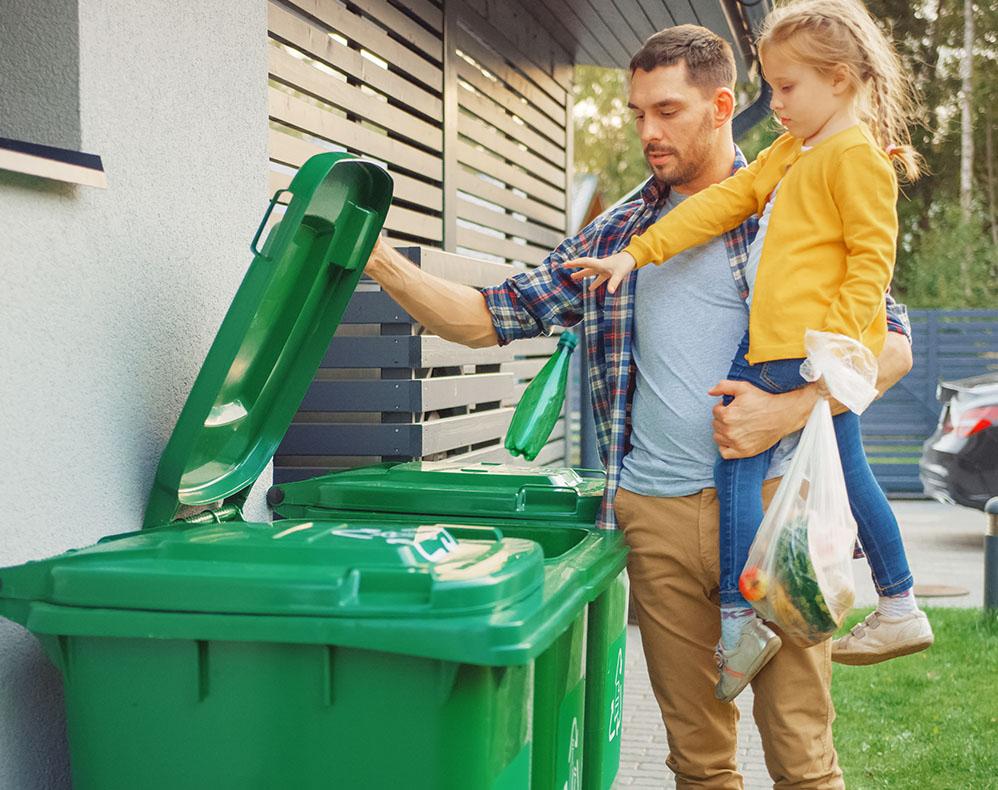 Image of caretaker and child putting plastic bottle into recycling