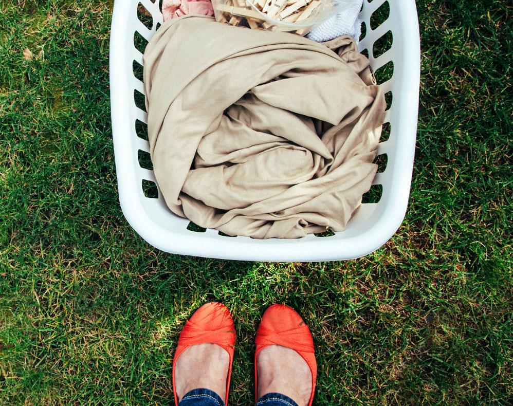 Person wearing red flats standing next to laundry basket on green lawn