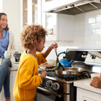 Family cooking together at gas stove