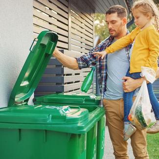 Image of caretaker and child putting plastic bottle into recycling