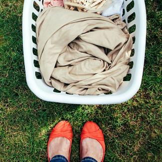 Person wearing red flats standing next to laundry basket on green lawn