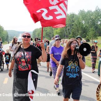 Protesters march on street. Youth speaks into megaphone.