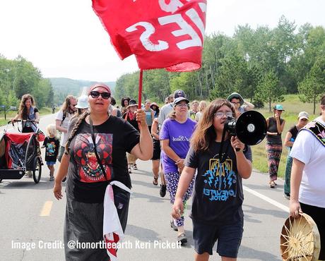 Protesters march on street. Youth speaks into megaphone.