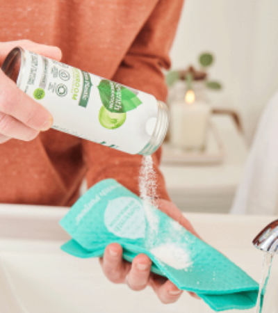 Zero Plastic Bathroom Cleaner Powder In Use - Person shaking powder onto damp cloth