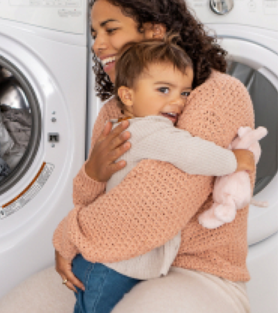 Adult and child embracing in front of laundry machine
