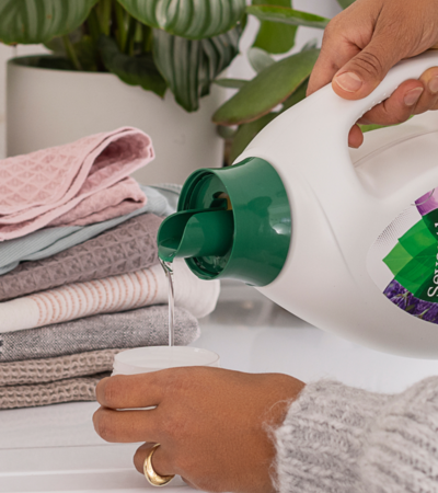 Person pouring laundry detergent into cap for dosage