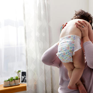 Parent holds toddler wearing Seventh Generation diaper