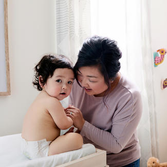 Parent leans towards baby who sits on diaper changing table