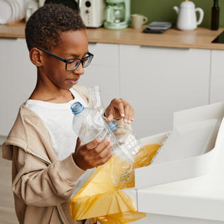 Child recycles bottles in kitchen