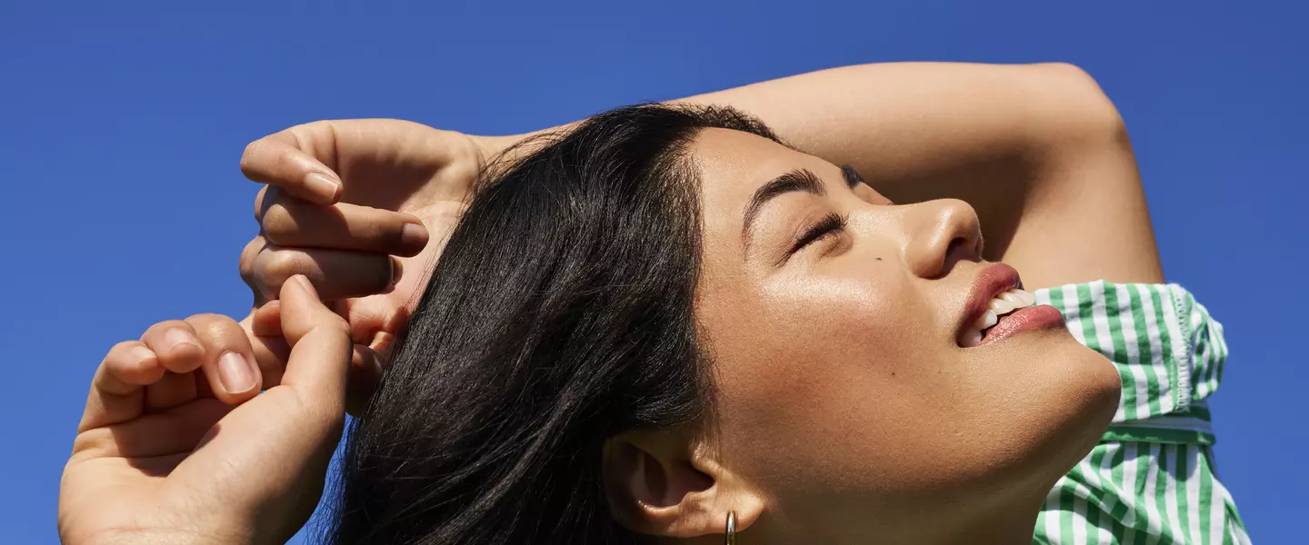 Person facing blue sky, smiling